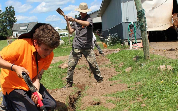 Young people use gardening tools during a service day with Outward Bound. 
